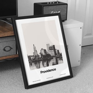 Op de afbeelding: Zwart-witfoto van de skyline van Providence, ingelijst in een zwart frame. De tekst "Providence" is onder de afbeelding gedrukt, samen met de locatie van de stad en de datum van oprichting.