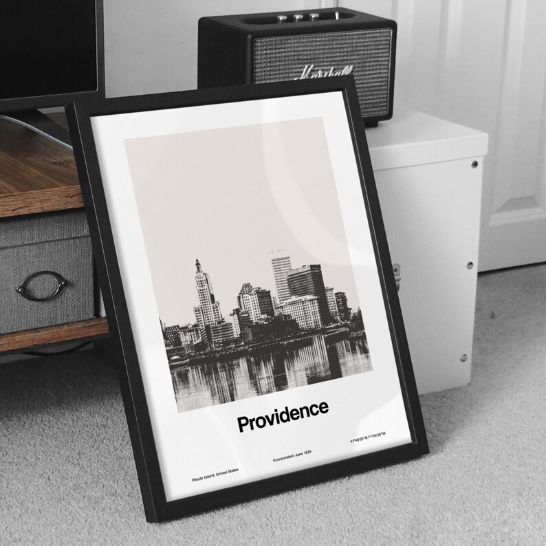 Op de afbeelding: Zwart-witfoto van de skyline van Providence, ingelijst in een zwart frame. De tekst "Providence" is onder de afbeelding gedrukt, samen met de locatie van de stad en de datum van oprichting.