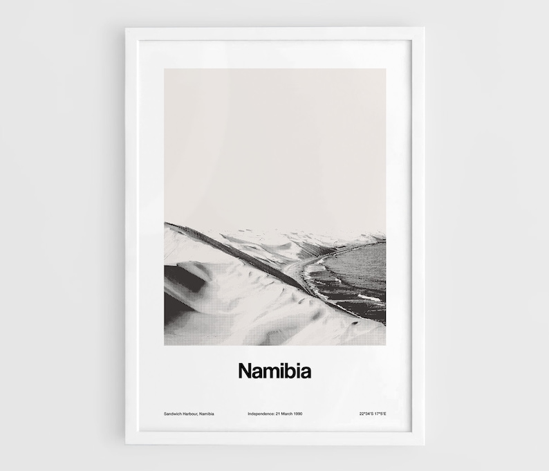 Op de afbeelding: Een zwart-witfoto van een woestijnlandschap in Namibi&euml;. De foto toont een zandstrand met een kustlijn en een bergketen op de achtergrond. De tekst "Namibi&euml;" is onder de afbeelding gedrukt.