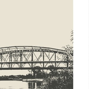 May include: A black and white image of a bridge with the text "T.G. OCEAN HIGHWAY" on the top. The bridge is made of metal and has a series of arches. The bridge is over a body of water and there are trees on either side of the bridge.