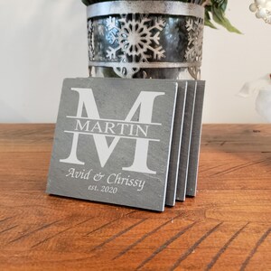 May include: Set of four gray slate coasters with white lettering. The coasters feature a large "M" with the name "Martin" centered below. The text "Avid & Chrissy est. 2020" is below the name.