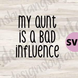 May include: A black and white graphic design on a wood background with the text "My aunt is a bad influence". A pink circle with the text "SVG" is in the lower right corner.