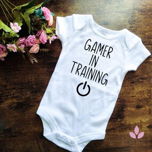 ゲーマートレーニングのベビーボディスーツ、ゲーマー向け幼児服、赤ちゃんのゲーム好きのお知らせ、お父さんへのかわいいゲームベビーシャワーギフト。パワーオン。