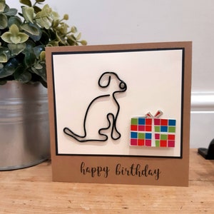 犬の誕生日おめでとうカード。手作り。カラフルなプレゼントカードを持ったラブラドール犬。