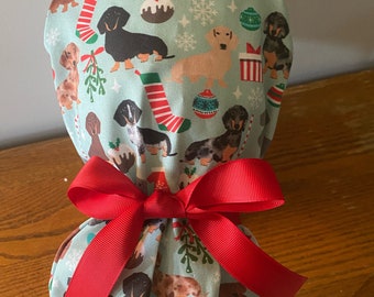 May include: A blue and white fabric shower cap with a Christmas-themed dachshund pattern. The cap is tied with a red ribbon.
