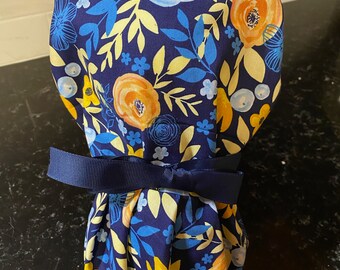 Puede incluir: Un gorro de quirófano azul y amarillo con estampado floral y un lazo azul marino.