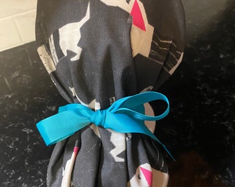 May include: A black fabric bag with a white dachshund pattern and pink accents. The bag is tied with a blue ribbon.