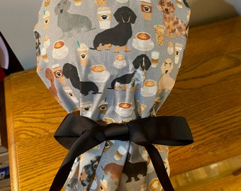 May include: A grey shower cap with a pattern of dachshunds and coffee cups. The cap is tied with a black ribbon.