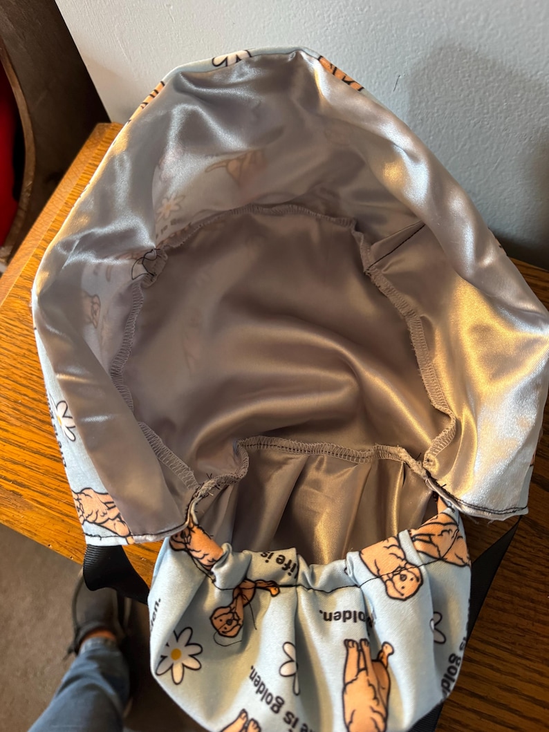 May include: A blue and white fabric bag with a satin lining. The bag has a repeating pattern of golden retriever dogs and the text "Life is Golden".