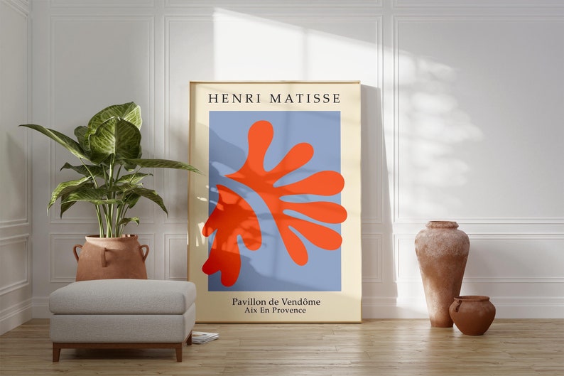 May include: A minimalist poster with a blue background and a large red abstract shape. The poster is framed in gold and has the text "HENRI MATISSE" at the top and "Pavillon de Vend&ocirc;me Aix En Provence" at the bottom.