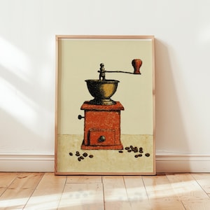 May include: A framed print of a vintage coffee grinder. The grinder is depicted in a warm, reddish-orange hue with a dark brown hopper and handle. Coffee beans are scattered around the base of the grinder, set against a neutral background.