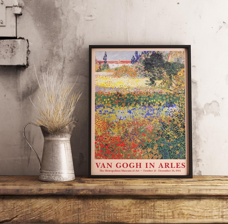 May include: A vintage poster for the exhibition "Van Gogh in Arles" at the Metropolitan Museum of Art. The poster features a painting of a field of flowers in various shades of red, yellow, blue, and green. The text "Van Gogh in Arles" is printed in red at the bottom of the poster.