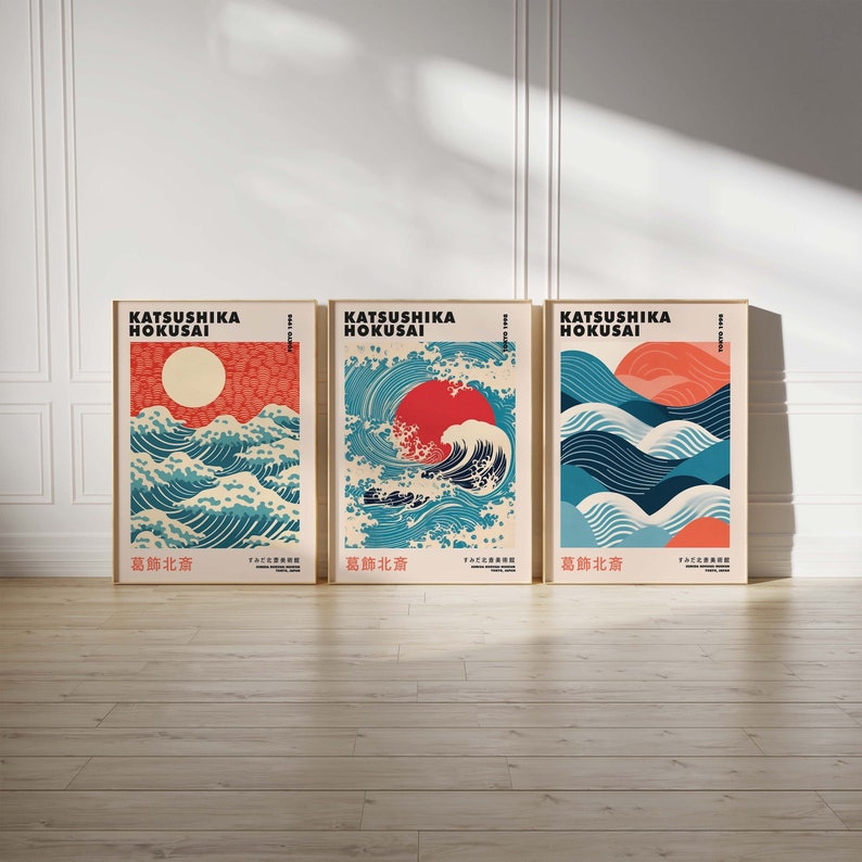 May include: Three framed prints of a Japanese wave design with a red sun rising above the waves. The prints are titled "Katsushika Hokusai" and "葛飾北斎" in Japanese.