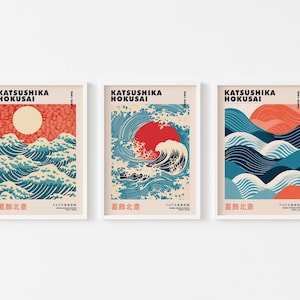 May include: Three framed prints of Japanese woodblock prints by Katsushika Hokusai, featuring the Great Wave off Kanagawa, with a red sun and blue and white waves. The text on the prints reads "Katsushika Hokusai" and "葛飾北斎".