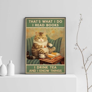 May include: A vintage-style poster featuring a cartoon cat sitting on a couch, reading a book and drinking tea. The text on the poster reads "That's what I do I read books I drink tea and I know things."
