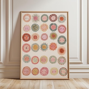 May include: A rectangular framed wall art print featuring a grid of thirty circular sun illustrations. Each sun has a unique face with closed eyes and a small mouth, rendered in various colors including pink, yellow, orange, green, and red.