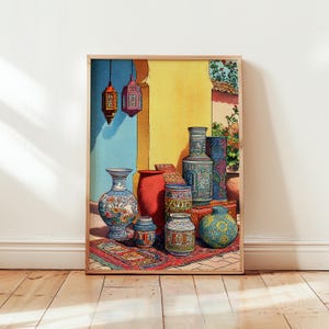 Op de afbeelding: Een ingelijste prent met een verzameling decoratieve vazen en lantaarns. De vazen zijn in verschillende maten en kleuren, waaronder blauw, rood en groen, met ingewikkelde patronen. De achtergrond omvat een gele en blauwe muur en een rood tapijt.