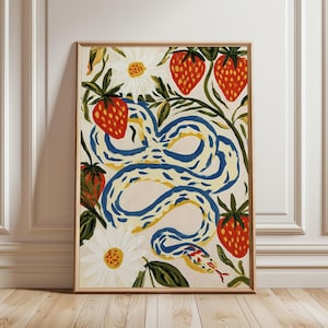 May include: A framed rectangular art print featuring a winding blue and yellow snake surrounded by red strawberries with green leaves and white daisy flowers with yellow centres on a light cream background, all enclosed in a light wood frame.