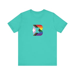 Puede incluir: Una camiseta de manga corta en un color turquesa claro sólido. Centrada en el pecho hay una letra B mayúscula grande rellena con un patrón de bandera del orgullo multicolor, con rayas horizontales de colores rojo, naranja, amarillo, verde, azul, morado, marrón, negro, azul claro, rosa y blanco.