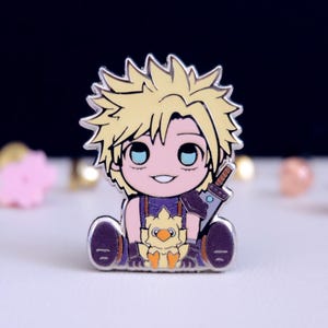 以下が含まれることがあります： 銀色のエナメルピンで、金髪碧眼のキャラクターが、紫と金の衣装を着て、剣と小さな黄色いひよこを持っている、ちびスタイルのイラストが描かれています。