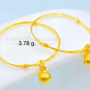 May include: Two gold bangles with small bells attached. The bangles are 3.78 grams in weight.