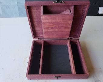 May include: An open wooden box with a purple stain finish. The box has a hinged lid and a brass latch. The interior of the box is lined with black felt and has three compartments.