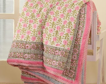 May include: A pink and green floral patterned quilt with a white background. The quilt has a pink and gray striped border.