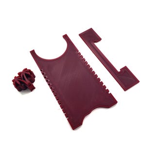 May include: A set of three red plastic tools for scraping and cleaning. The tools are shaped like a comb, a rectangle with a cut-out, and a palm tree.