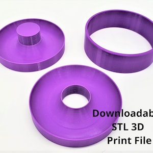 Op de afbeelding: Drie paarse 3D-geprinte donutvormen. De vormen zijn ontworpen om donuts te maken met een gat in het midden. De tekst "Downloadbaar STL 3D-printbestand" is zichtbaar in de afbeelding.