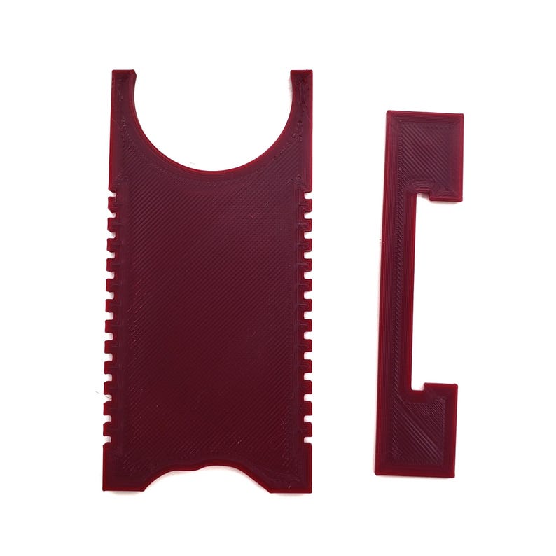 May include: A red plastic tool with a handle and a serrated edge. The tool is designed to scrape and clean surfaces.