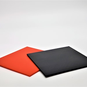 May include: Two square pieces of material, one red and one black, are stacked on top of each other. The red piece is on the bottom and the black piece is on top.