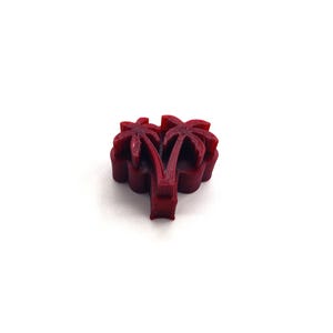 May include: A 3D printed red palm tree design. The palm tree is made of multiple layers of plastic.