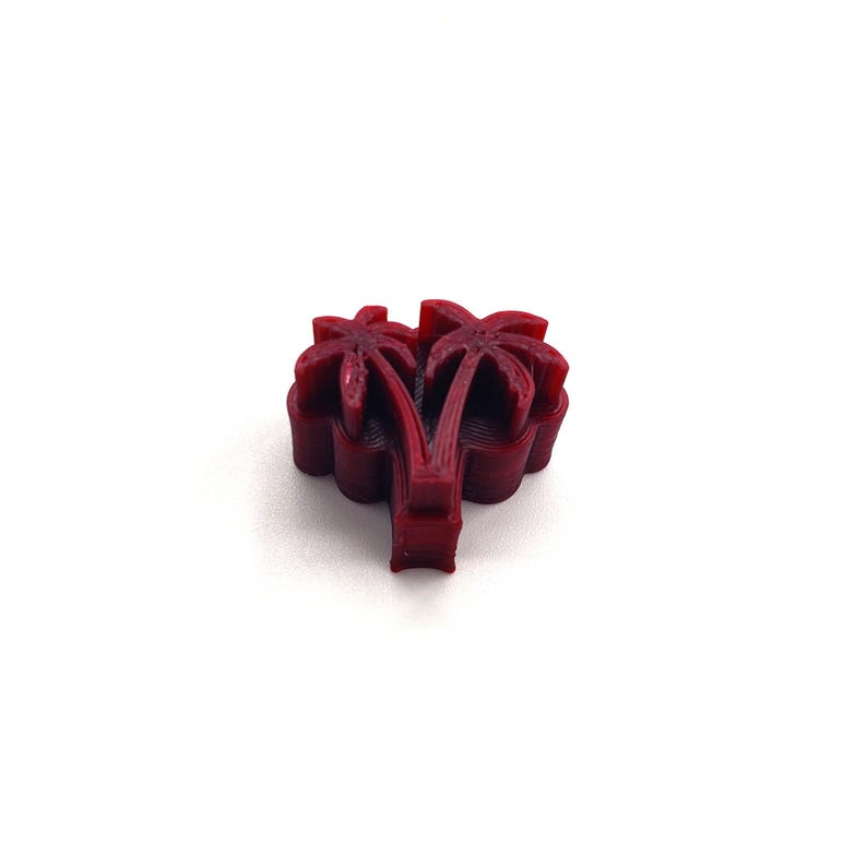 May include: A 3D printed red palm tree design. The palm tree is made of multiple layers of plastic.