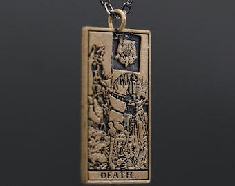May include: A gold-toned necklace with a pendant featuring a tarot card design. The card depicts a skeletal figure riding a white horse and the word "DEATH" is printed at the bottom.