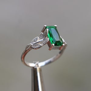 以下が含まれることがあります： 緑のエメラルドと葉のディテールが施されたシルバーリング
