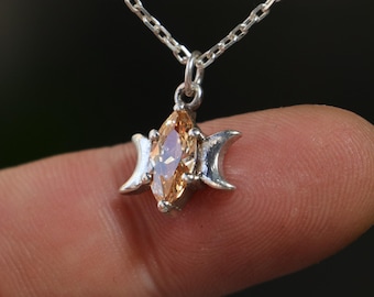 May include: A silver necklace with a pendant featuring a triple moon design and a marquise-shaped topaz gemstone.