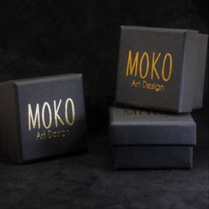 May include: Three black boxes with gold lettering that reads "MOKO Art Design".