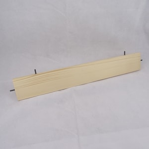 May include: A light wood shelf with metal brackets. The shelf is approximately 76 cm long.