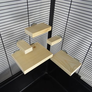 May include: Five wooden shelves for a small animal cage. The shelves are made of natural wood and are attached to the cage with metal clips. The shelves are different sizes and shapes, providing a variety of levels for the animal to explore.