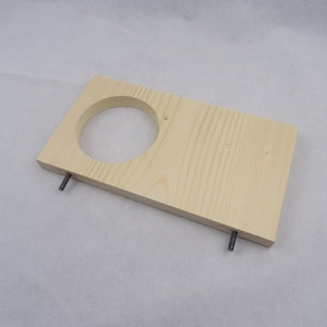 May include: A wooden shelf with a circular cutout and two metal screws. The shelf is light brown and has a natural wood grain.