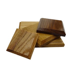 May include: A selection of wooden plaques in shades of brown. The plaques are square or rectangular, with some having beveled edges. The wood grain is visible, and the finish appears smooth and polished. The plaques are stacked and arranged in a visually appealing way.