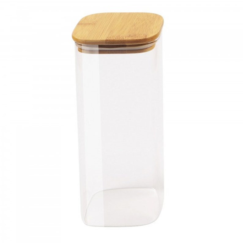 May include: A clear glass storage jar with a square bamboo lid. The jar is tall and rectangular.