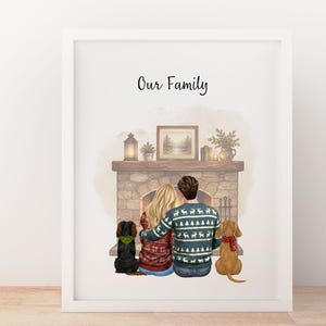 May include: A framed print titled Our Family featuring an illustration of two people sitting before a stone fireplace with two dogs. The people wear patterned sweaters, and the dogs wear scarves. A lantern, plant, and framed picture sit on the mantel.