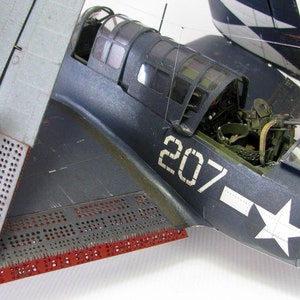 May include: A close-up of a blue and gray model airplane with the number 207 painted on the side. The airplane has a white star on the fuselage and a machine gun mounted on the top.