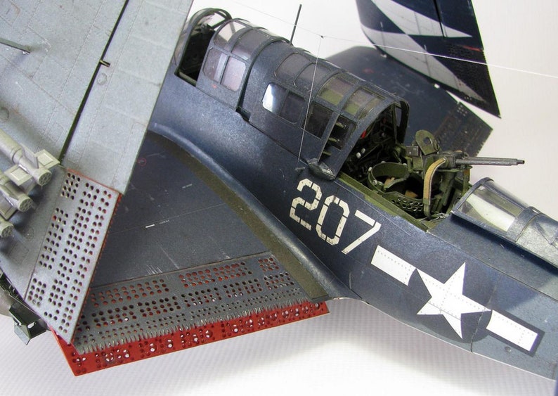 May include: A close-up of a blue and gray model airplane with the number 207 painted on the side. The airplane has a white star on the fuselage and a machine gun mounted on the top.