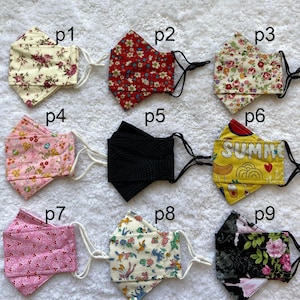 Pode incluir: Nove m&aacute;scaras de tecido diferentes com v&aacute;rios padr&otilde;es e cores. As m&aacute;scaras est&atilde;o todas dobradas ao meio e t&ecirc;m la&ccedil;os el&aacute;sticos para as orelhas. Os padr&otilde;es incluem desenhos florais, de bolinhas e geom&eacute;tricos. As m&aacute;scaras est&atilde;o etiquetadas com os n&uacute;meros p1 a p9.