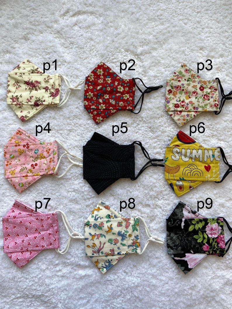 Pode incluir: Nove m&aacute;scaras de tecido diferentes com v&aacute;rios padr&otilde;es e cores. As m&aacute;scaras est&atilde;o todas dobradas ao meio e t&ecirc;m la&ccedil;os el&aacute;sticos para as orelhas. Os padr&otilde;es incluem desenhos florais, de bolinhas e geom&eacute;tricos. As m&aacute;scaras est&atilde;o etiquetadas com os n&uacute;meros p1 a p9.