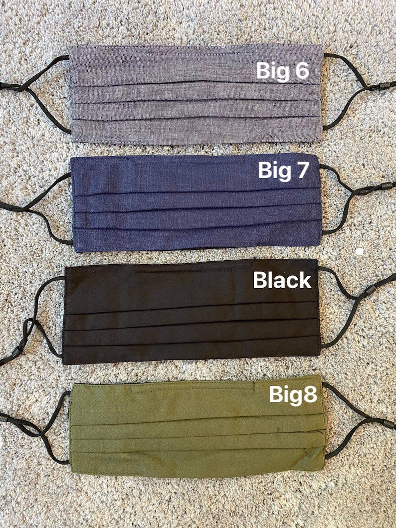 Pode incluir: Quatro m&aacute;scaras de tecido com la&ccedil;os el&aacute;sticos para as orelhas. As m&aacute;scaras s&atilde;o de cor cinza, azul, preto e verde. As m&aacute;scaras s&atilde;o etiquetadas como "Big 6", "Big 7", "Black" e "Big 8".