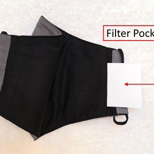 Pode incluir: M&aacute;scara facial de tecido preto e cinza com um bolso para filtro. O bolso est&aacute; etiquetado como "Filter Pocket!"