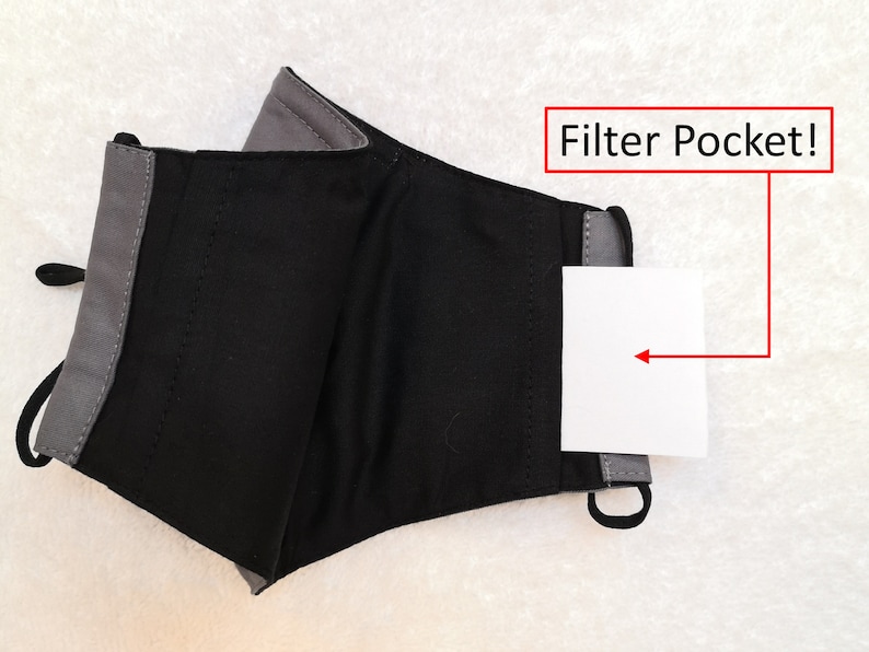 Pode incluir: M&aacute;scara facial de tecido preto e cinza com um bolso para filtro. O bolso est&aacute; etiquetado como "Filter Pocket!"